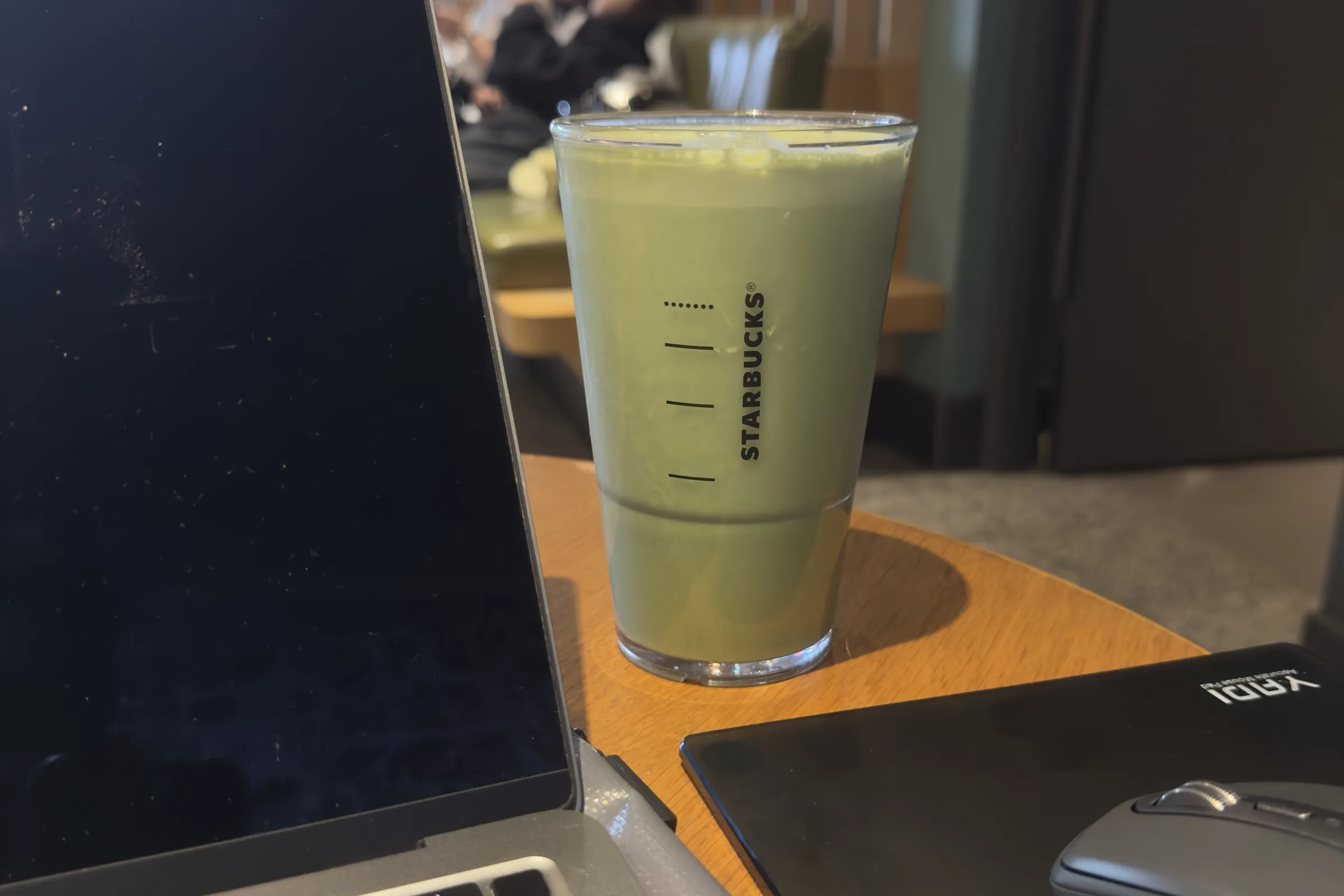 咖啡廳桌上的 MacBook、抹茶拿鐵與滑鼠
